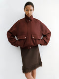 Proenza Schouler Editorial image of model standing against white wall wearing the Aviva Jacket in Wool Gabardine in Oxblood with the Saski Dress in Cotton in Textured Fringe in Earth