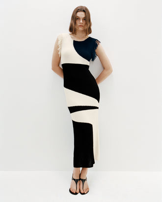 Proenza Schouler Campaign image of model wearing Saskia Dress in Textured Fringe Intarsia in Sand Multi with the Tee Thong Sandals in Slick Nappa in Black