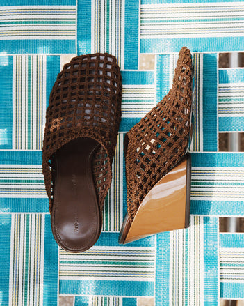 Still life of  slant crochet mules on blue striped beach chair