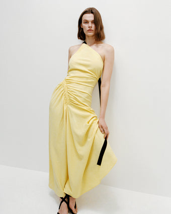 Model wearing Sirena dress leaning against white wall