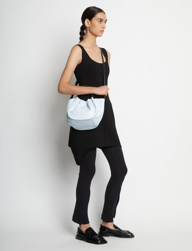 Image of model carrying Small Ruched Crossbody Tote in PALE BLUE across the shoulder