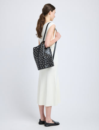 Image of model wearing Brant Bucket Bag in Eyelet Covered Smooth Calf in Black
