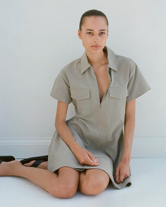 Image of model sitting wearing Carmine Dress in Solid Crinkle Cotton in bayleaf