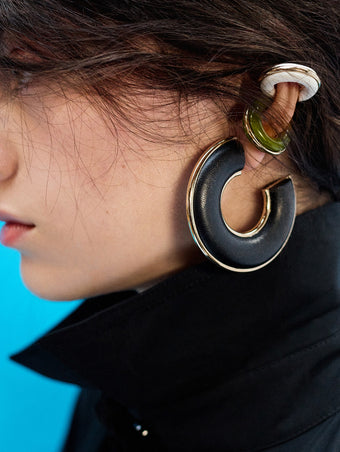 Proenza Schouler Editorial image of model wearing Leather Hoop Earrings in black and Mini Hoop Earrings in olive and optic white