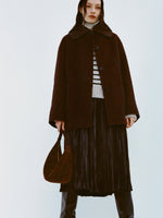 Image of model wearing Lisa Coat in Double Face Wool in Hickory and Rosalyn Skirt in Faux Leather in Black and black boots on a white background