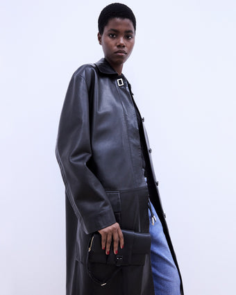 Cropped image of model wearing Billie Coat in Leather in black and carrying black Flip Bag
