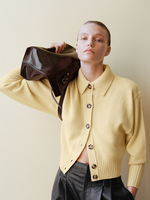 Proenza Schouler Front cropped image of model wearing Rocio Cardigan in Cashmere in Pale Yellow holding the Days Tote