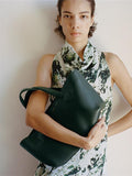 Proenza Schouler Front full length image of model wearing Adelide Dress in Printed Silk Viscose in Dark Green Multi holding the East West Chelsea Tote in Pebbled Calf Bottle.