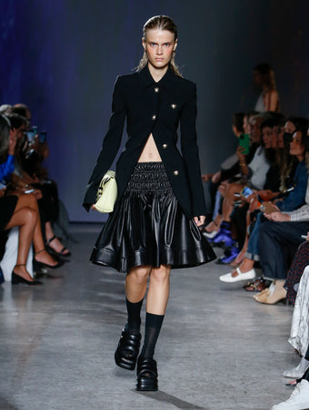 model wearing black coat and black skirt