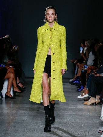 model wearing yellow tweed coat and black skort