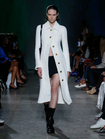 model wearing white coat and black skort