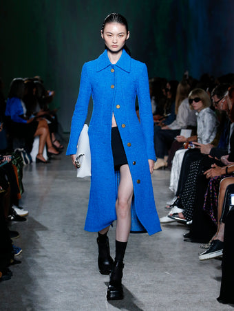 model wearing blue coat and black skort