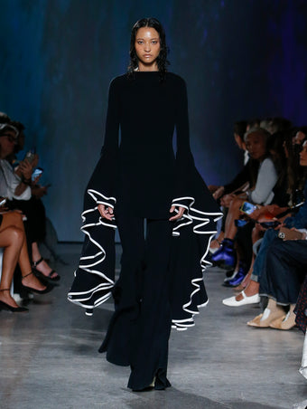 model wearing black ruffle sleeve dress and pants