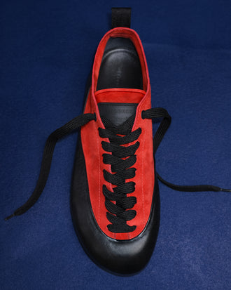 Proenza Schouler editorial image of Arcadia Sneakers in red with black laces on a blue background. 