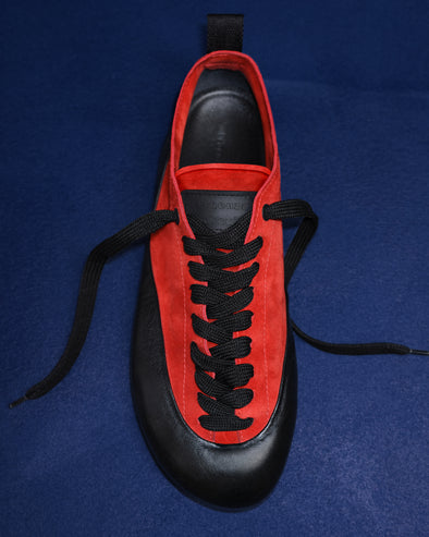 Proenza Schouler editorial image of Arcadia Sneakers in red with black laces on a blue background. 