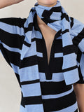 Proenza Schouler Editorial image of model wearing Solana Dress in Superfine Merino Silk in Black Multi with Gia Top in Superfine Merino Silk in Blue Multi wrapped around her neck. 