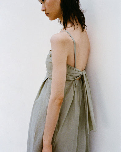 Cropped image of model standing against a white backdrop wearing the Claudine Dress in Tech Poplin in Sage