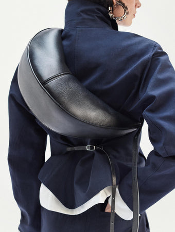 Cropped image of model standing against white backdrop Slide bag in Black and Thelma Jacket in Cotton Linen Suiting in Navy
