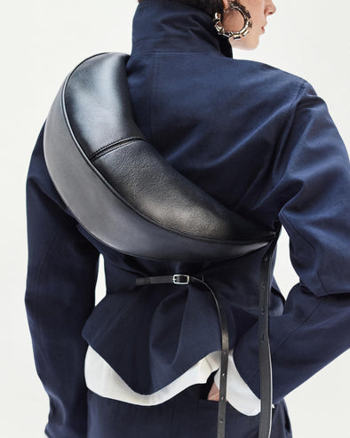 Cropped image of model standing against white backdrop Slide bag in Black and Thelma Jacket in Cotton Linen Suiting in Navy