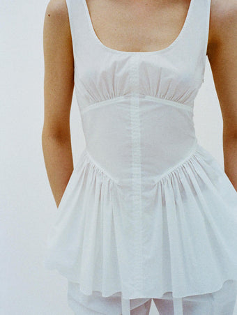 Cropped image of model standing in front of a white backdrop, wearing Bader Top in Stretch Poplin in White