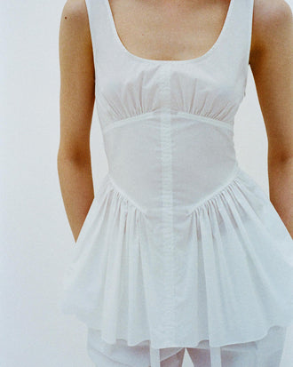 Cropped image of model standing in front of a white backdrop, wearing Bader Top in Stretch Poplin in White
