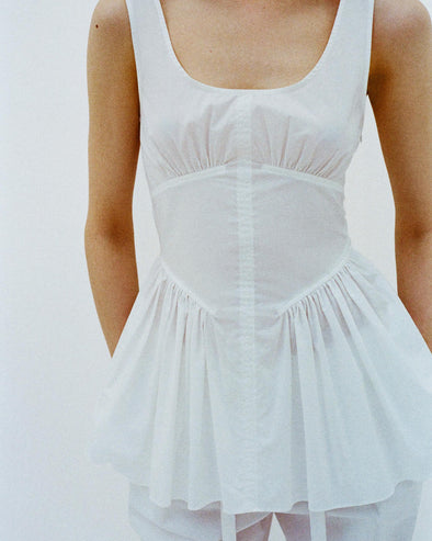 Cropped image of model standing in front of a white backdrop, wearing Bader Top in Stretch Poplin in White