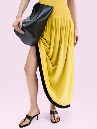 Cropped image of model standing against a pink backdrop wearing Cable T Strap Sandals in Black