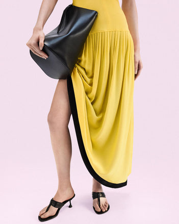 Cropped image of model standing against a pink backdrop wearing Cable T Strap Sandals in Black