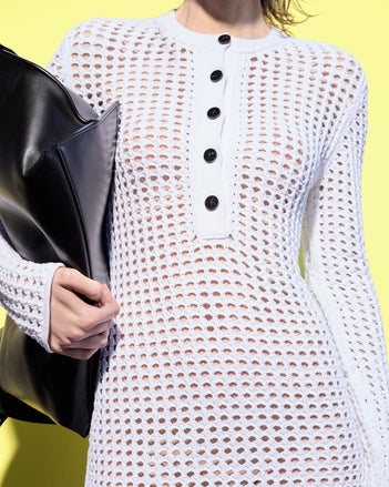 Cropped image of model standing in front of a yellow backdrop, wearing Micah Dress in Open Crochet in Off-White