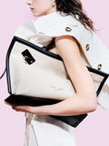Cropped image of model standing against pink backdrop wearing Days Tote in Natural Linen