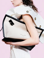 Cropped image of model standing against pink backdrop wearing Days Tote in Natural Linen