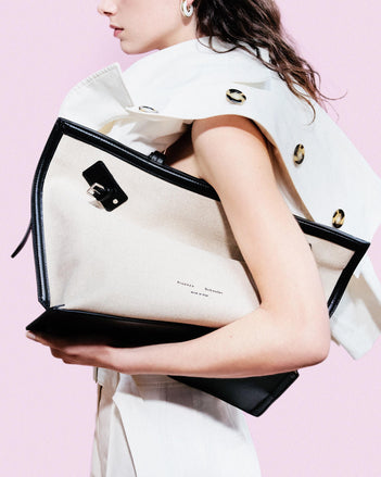 Cropped image of model standing against pink backdrop wearing Days Tote in Natural Linen