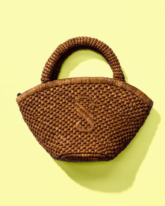 Front image of Small Chelsea Tote in Natural Raffia in Honey on a yellow backdrop