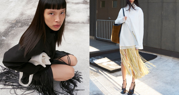 Diptych image of Image of model crouching on concrete ground wearing Sibyl Jacket in Stretch Nylon in black with Veda Skirt in Faux Leather Fringe in black and model standing against industrial background wearing Addy Top in white and Veda Skirt in Faux Leather Fringe in pale yellow multi, carrying Brant Bucket Bag in suede in fern