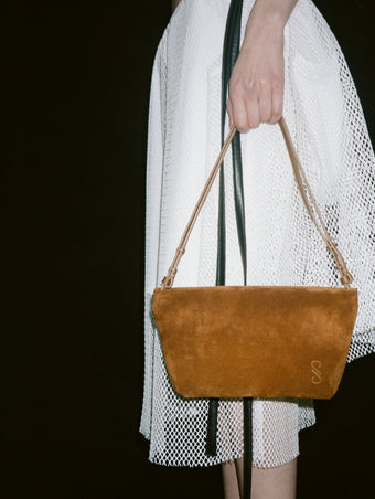 Cropped image of a model's hand holding Bond Bag in Suede in saddle.