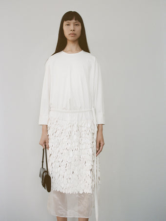 Cropped image of a model wearing Olson T-Shirt in Eco Cotton Jersey in white, carrying a Flip Shoulder Bag in Eel in black.