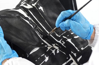 In process image of artisan hand painting dye onto garment printed Ryman Jeans in black multi