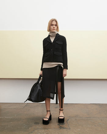PF23 Collection Look 15: Black Bi-Stretch Tweed Jacket, Oatmeal Doubleface Cashmere Turtleneck, Black Crepe Chiffon Skirt, Black Drawstring Shoulder Bag, and Black Velvet Square Platform Sandals
