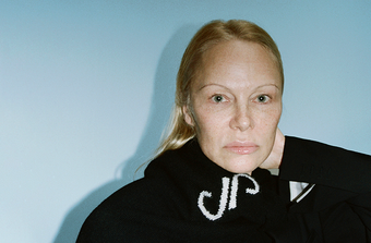 Cropped image of Pamela Anderson wearing Stella Monogram Sweater in Cashmere Jacquard in black around her neck