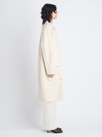 Side image of model in Billie Coat In Lacquered Leather in ecru