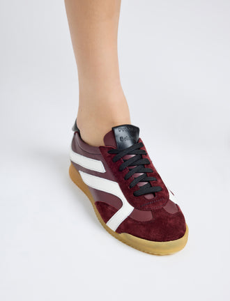 On model image of Track Sneakers in colorway Oxblood and ivory stripes.