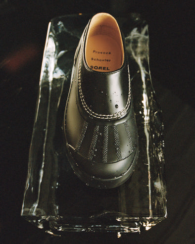 Aerial image of SchoulerSOREL x Proenza Schouler Caribou Mules in black/chalk, sitting on block of ice