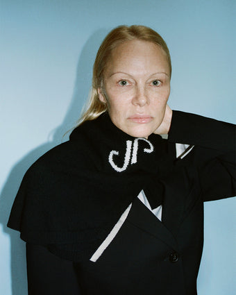 Cropped image of Pamela Anderson wearing Stella Monogram Sweater in Cashmere Jacquard in black around her neck