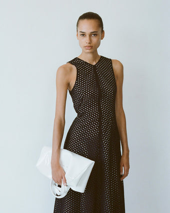Model wearing Juno Dress in Broderie Anglaise in black, carrying Spring Tote in optic white