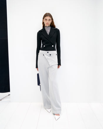 Model wearing Cropped image of model wearing Prescott Top in Matte Viscose Crepe in black, Marine Jacket in Bi-Stretch Suiting in black, and Oliver Pant in Wool Gabardine in grey, holding Silo Bag in Kid Suede in navy