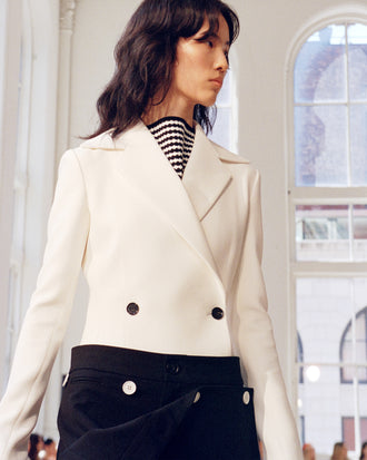 Model walking Proenza Schouler SS25 Runway show wearing Marine Jacket in Bi-Stretch Suiting in off white and Oliver Pant in Wool Gabardine in black