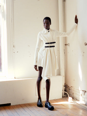 Model wearing Reinhardt Dress in Wool Cashmere in off white and SOREL x Proenza Schouler Caribou Mules in black/chalk