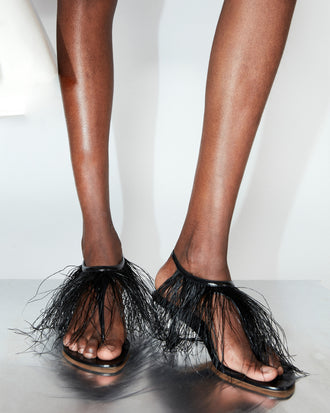 Cropped image of model wearing Tee Thong Feather Sandals in black