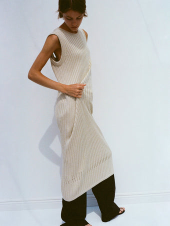 Model wearing Leighton Knit Dress in Dry Rib in light wheat, adjusting fabric with her hands