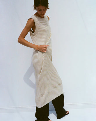 Model wearing Leighton Knit Dress in Dry Rib in light wheat, adjusting fabric with her hands